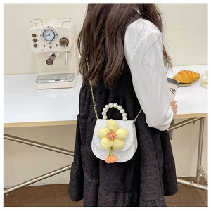 Mini sac matelassé blanc pour fille avec fleur jaune et poignée en perles dans un café
