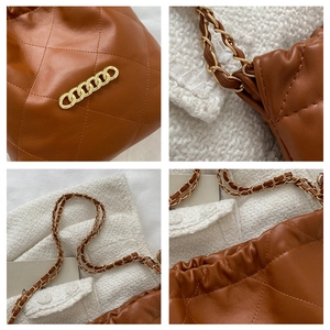 Detailed macro view of caramel quilted leather and premium gold metal chain strap on tote bag