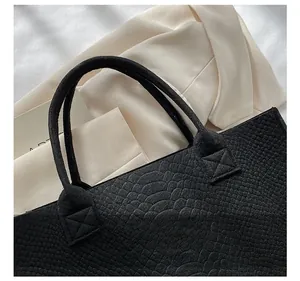 Close-up of black crocodile pattern tote bag with reinforced stitching and handle