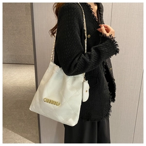 White quilted chain tote bag worn by model showing side profile in a minimalist interior