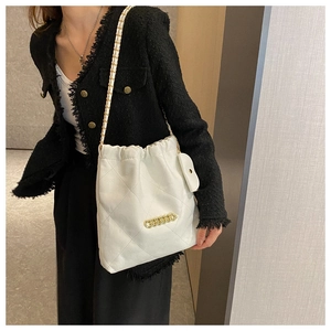 Detail of white quilted drawstring bucket bag with gold chain and matching charm pouch
