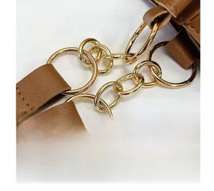 Dettaglio della catena dorata che collega la tracolla in pelle marrone della borsa tote
