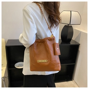 Close-up of brown quilted leather tote with chunky gold chain detail and mini pouch