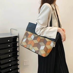 Detail of large tote bag with black leather and colorful geometric cube patterns