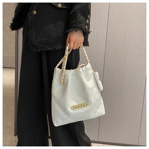 Detail of white quilted tote bag with gold chain strap and mini coin purse pendant