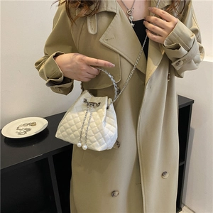 Chic beige quilted bucket bag with pearl drawstring charms and silver chain strap