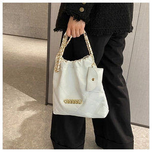 Detail of white quilted bucket bag with gold chain strap and mini purse accessory