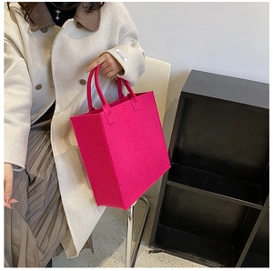 Detail of magenta felt tote bag showing textured surface and minimalist handle design