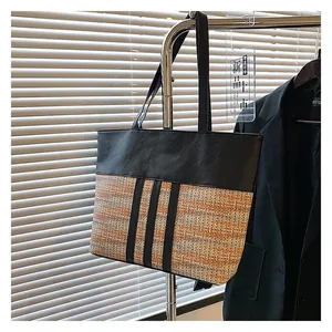 Detail of large tote bag with black leather and colorful woven fabric texture on a hanger