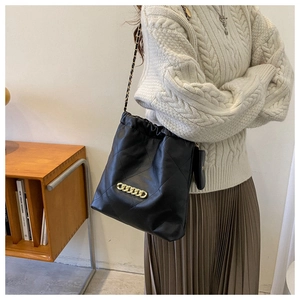 Close-up of black quilted leather shoulder bag with gold chain and drawstring closure