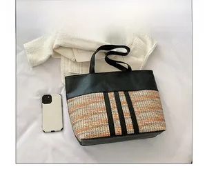 Detail of color-block tote bag featuring black faux leather and woven straw texture