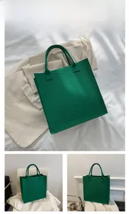 Detailed close-up showing the green crocodile pattern texture on the leather tote bag