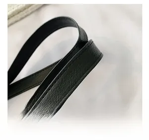 Close-up of black leather handle with litchi grain texture and precise stitching detail