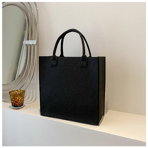 Detail of black faux crocodile skin texture and sturdy handles on the tote bag