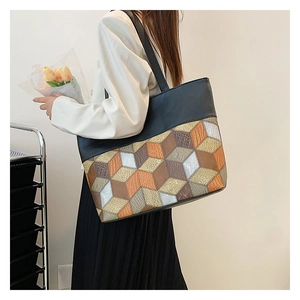 Detail showing colorful geometric patchwork and leather texture of a large tote bag