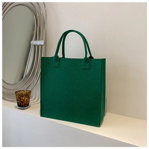Detailed texture of green felt tote bag featuring an embossed snakeskin pattern