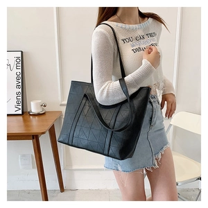 Lifestyle shot of large black tote bag with geometric embossed pattern and dual handles