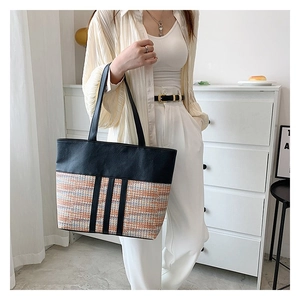 Detail of multi-color tweed stitching and black leather straps on a large tote bag