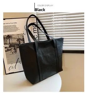Detail view of black tote bag with geometric triangular texture on white table