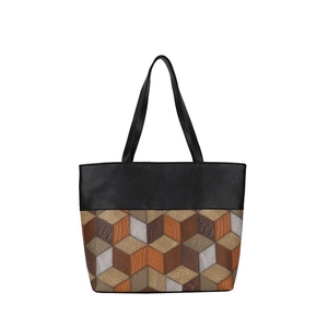 Detail view of large tote bag featuring black leather and 3D geometric patchwork patterns