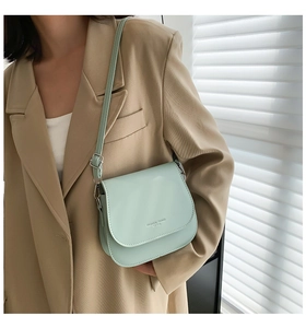 Détail d'un petit sac bandoulière vert menthe avec boucle argentée porté par un mannequin