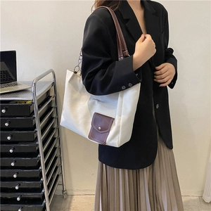 Minimalist white canvas tote bag with brown leather pocket and chain strap for women