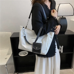 Minimalist black and white canvas tote bag with leather strap and metal chain details