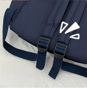 Detail of adjustable shoulder straps with black plastic buckles on a navy nylon backpack