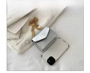 Size comparison of silver mini chain bag next to a smartphone showing compact dimensions
