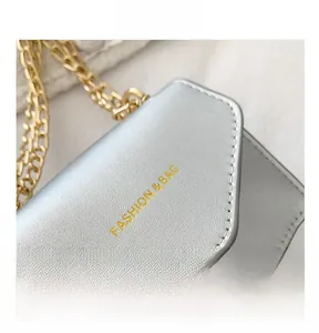 Macro detail of silver mini bag with gold chain strap and 'FASHION & BAG' gold lettering