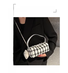 Detail of tweed check boston bag featuring a white bear charm and metal chain strap