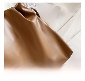 Detailed macro view of soft brown leather texture with natural pleated folds on bucket bag