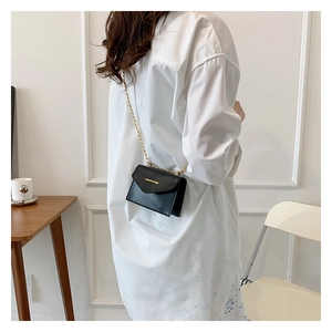 Detail view of mini black crossbody bag with gold chain strap and fashion lettering