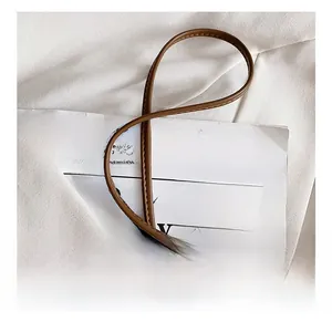 Detail of a dark brown leather bucket bag strap with precise stitching and circular design