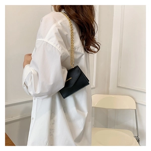 Mini black envelope chain bag shown on a model with minimalist white background styling