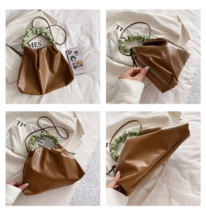 Detail view showing caramel brown pleated bucket bag with green ruched handle and metal zipper