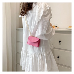 Chic pink mini envelope bag featuring a delicate gold chain strap and polished flap detail
