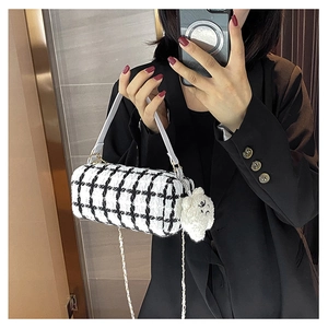 Detail of checkered cylinder bag with gold chain strap and cute dog pendant accessory