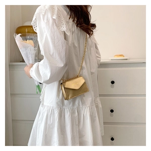 Chic champagne gold mini chain crossbody bag styled with a white lace dress and flowers