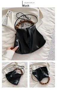 Detail view of black pleated bucket bag with brown scrunchie handle and shoulder strap