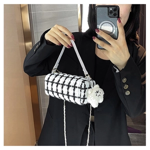 Detail of black and white tweed barrel bag with gold chain and white bear charm