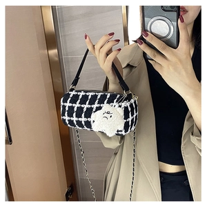 Detail of checkered barrel crossbody bag featuring a plush star charm and chain strap