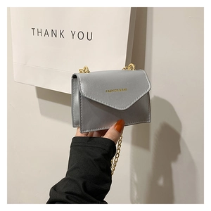 Close-up of silver-grey mini chain bag featuring gold FASHION & BAG lettering detail