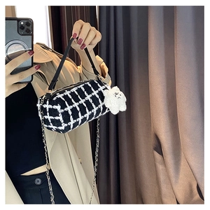 Detail of checkered barrel bag with black leather handle and plush cloud charm