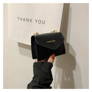 Detailed view of the black mini chain bag featuring a gold fashion logo and sleek PU leather