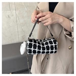 Detail of checkered cylinder bag with leather handle and white pompom accessory