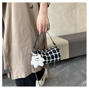 Detail showing checkered tweed cylinder bag with leather handle and star charm