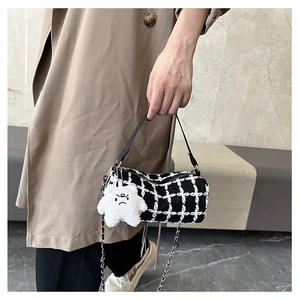 Close-up of black and white plaid cylinder bag with leather handle and star charm