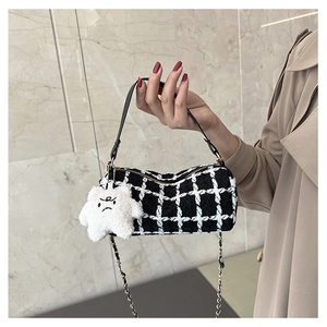 Detail of checkered tweed cylinder bag with gold chain and plush star charm accessory