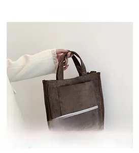 Macro detail of the brown corduroy tote bag showing front pocket and striped texture